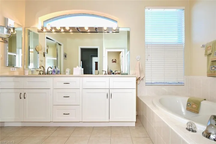 Full bathroom with light tile patterned flooring, double vanity, and a garden tub
