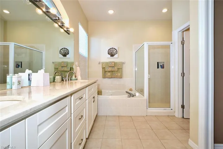 Full bath with a bath, a shower stall, double vanity, light tile patterned flooring, and recessed lighting