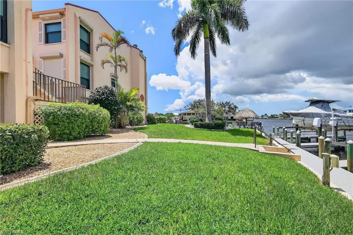 View of grassy yard featuring a water view, a dock, and boat lift