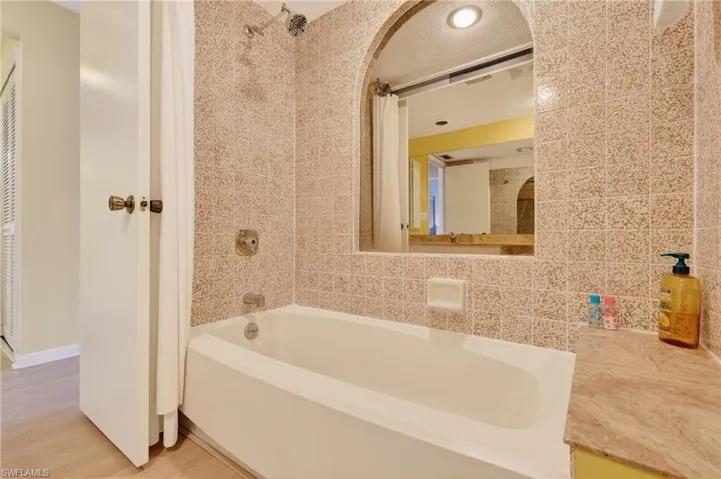 Bathroom with tile walls, shower / bathtub combination