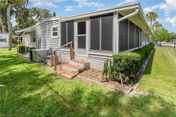 Rear view of house with entry steps, a sunroom, and a yard