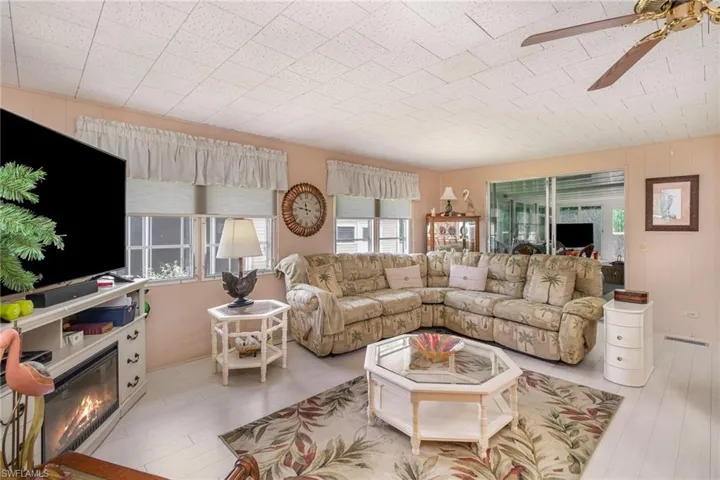 Living room featuring a ceiling fan, a glass covered fireplace, and wood finished floors