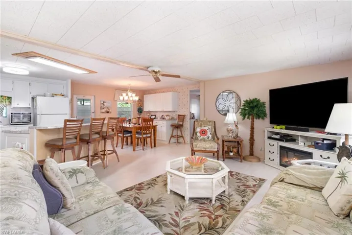 Living room with a ceiling fan, a glass covered fireplace, a chandelier, and light wood-style floors