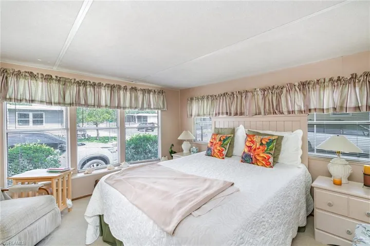 Bedroom featuring multiple windows and light carpet