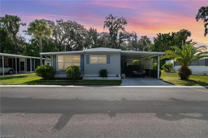 Manufactured / mobile home with a carport, a lawn, concrete driveway, and a metal roof