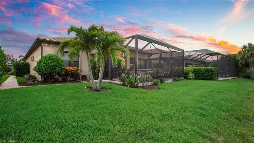 Back of property with a yard, stucco siding, a lanai, and a tiled roof
