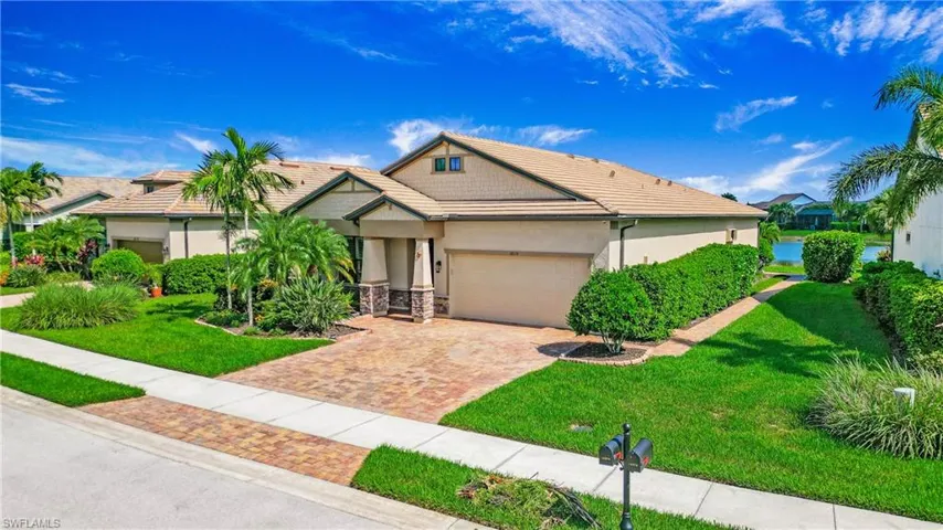 View of front of house featuring a tile roof, a garage, decorative driveway, a front yard, and stucco siding
