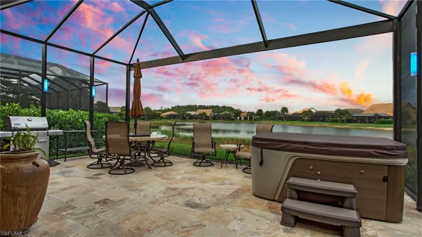 View of patio / terrace with a hot tub, grilling area, a water view, outdoor dining space, and a lanai