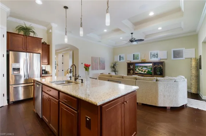 Kitchen with stainless steel appliances, arched walkways, a ceiling fan, dark wood-style floors, and coffered ceiling