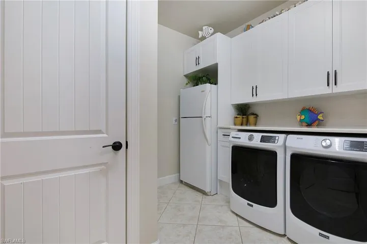 Laundry room with washer and dryer, cabinet space, and light tile patterned floors