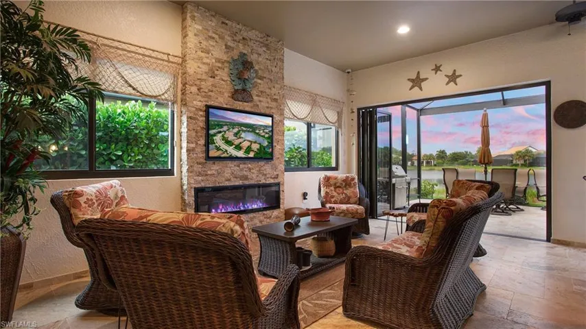 Living room featuring stone tile flooring, a stone fireplace, a textured wall, a water view, and recessed lighting