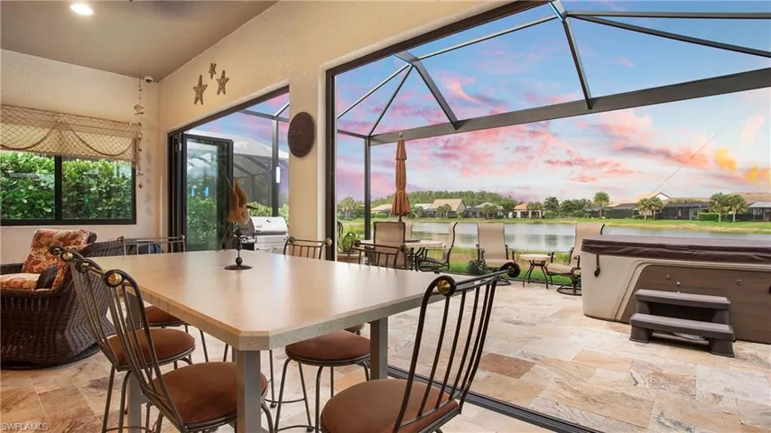 View of patio with a hot tub, a water view, a lanai, outdoor dining area, and grilling area