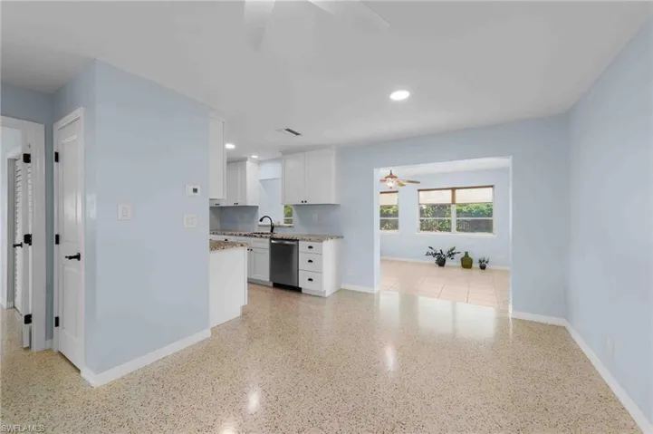 Kitchen with ceiling fan, dishwasher, a sink, baseboards, and white cabinetry