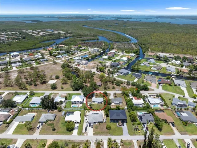 Aerial view of property and surrounding area featuring a large body of water, nearby suburban area, and a forest
