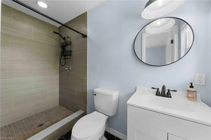 Full bathroom with toilet, vanity, and a tile shower