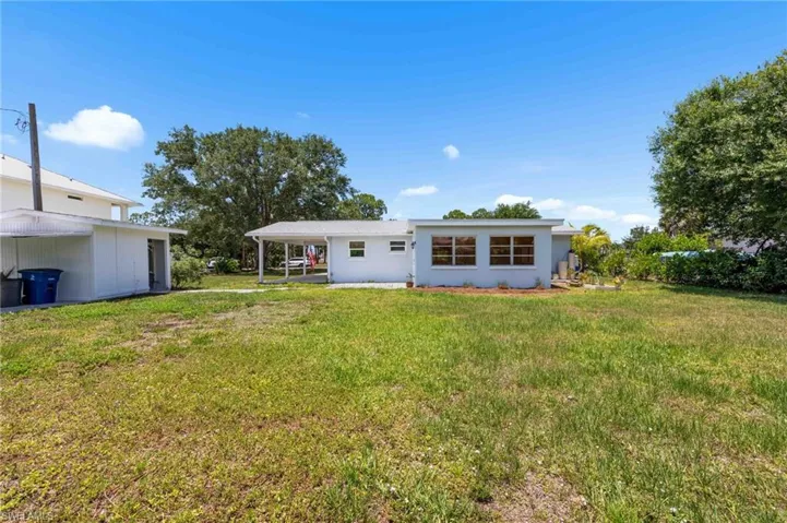 Back of house featuring an attached carport, a yard, and stucco siding