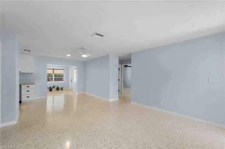 Unfurnished living room featuring a ceiling fan, speckle patterned floor, and baseboards