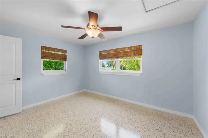 Unfurnished room with speckled floor, healthy amount of natural light, and baseboards