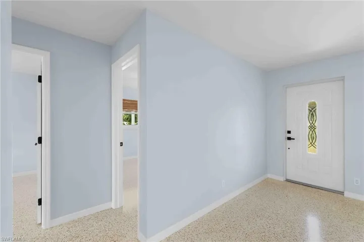 Foyer entrance featuring speckle patterned floor and baseboards