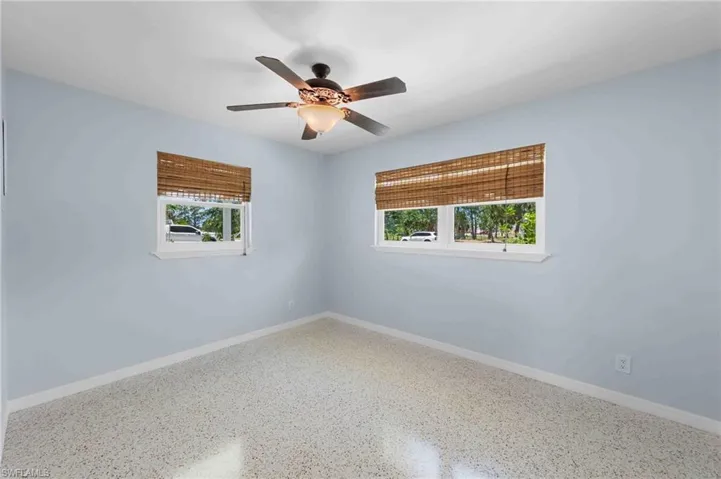 Spare room with speckle patterned floor, healthy amount of natural light, a ceiling fan, and baseboards