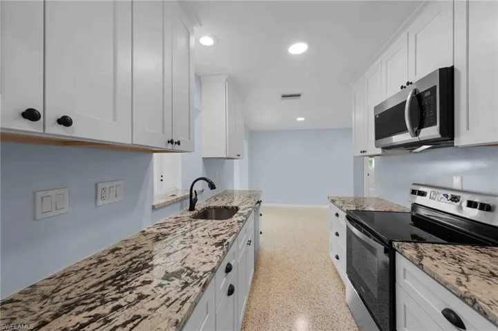 Kitchen featuring appliances with stainless steel finishes, a sink, white cabinetry, and recessed lighting