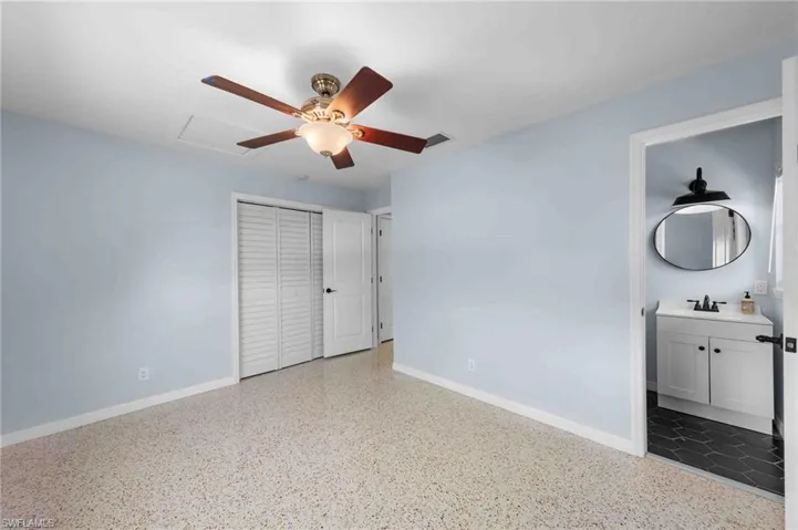 Unfurnished bedroom with baseboards, speckle patterned floor, a closet, and a sink