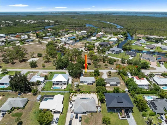Aerial view of property and surrounding area with a nearby body of water, nearby suburban area, and a forest
