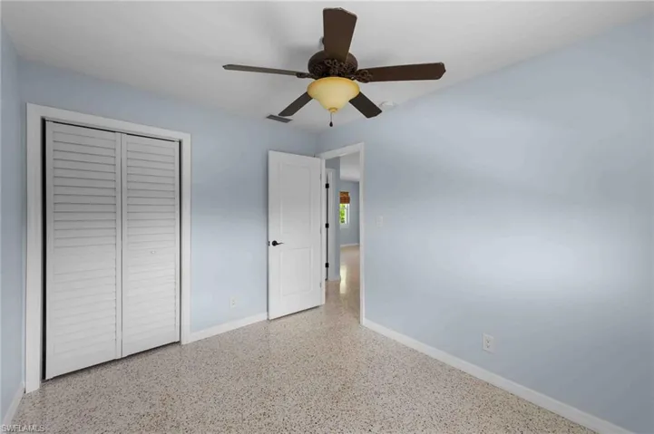 Unfurnished bedroom featuring baseboards, speckled floor, a closet, and a ceiling fan