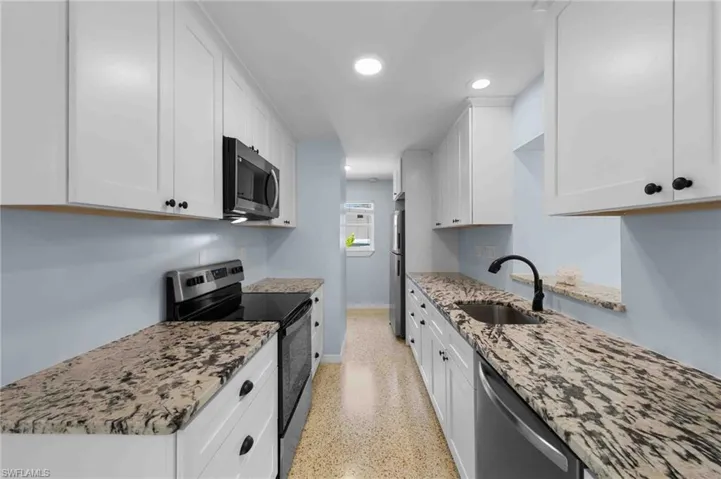 Kitchen with stainless steel appliances, a sink, baseboards, white cabinets, and recessed lighting