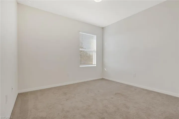 Empty room featuring light colored carpet and baseboards
