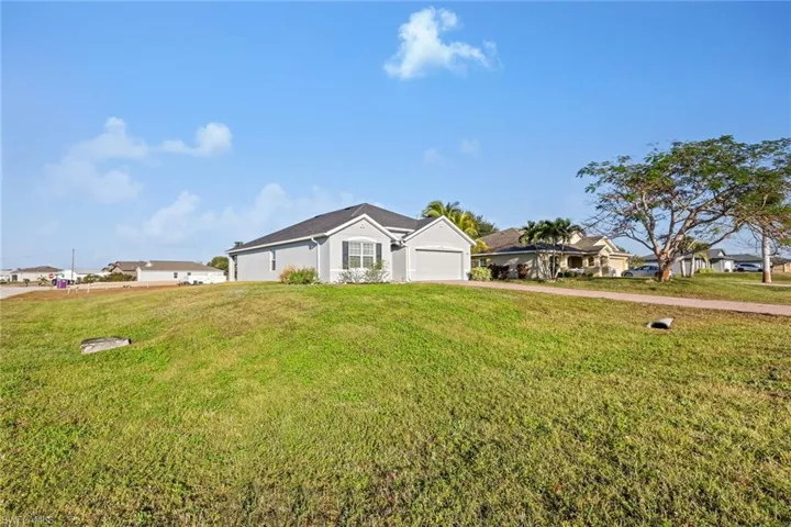 Ranch-style home featuring a front lawn, driveway, and a garage