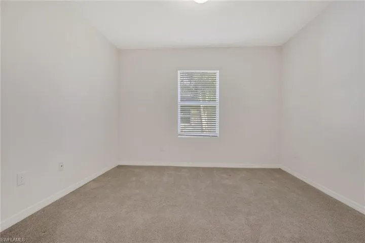 Spare room with light colored carpet and baseboards