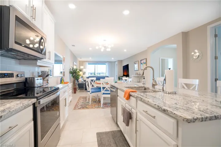 Kitchen with appliances with stainless steel finishes, decorative backsplash, sink, a center island with sink, and light tile patterned floors