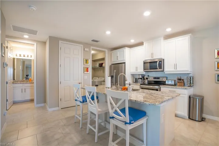 Kitchen with appliances with stainless steel finishes, an island with sink, light tile patterned floors, and tasteful backsplash