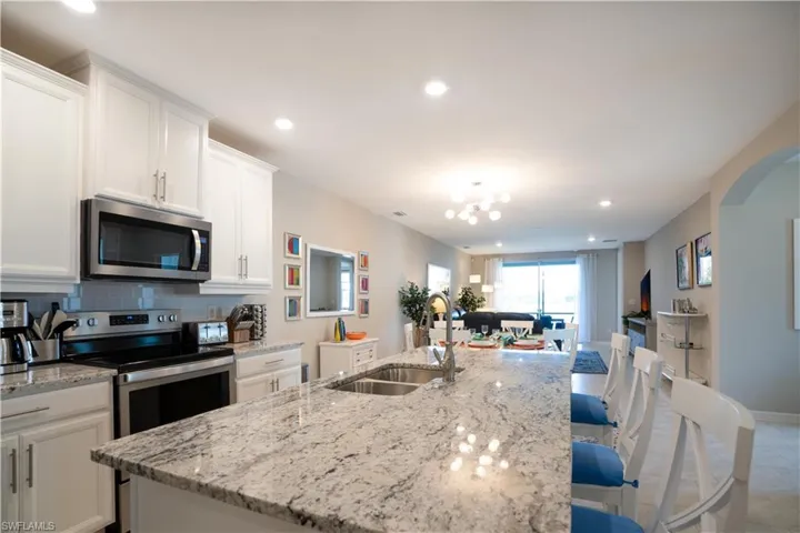 Kitchen with appliances with stainless steel finishes, sink, decorative backsplash, and an island with sink