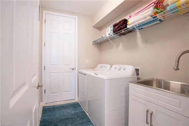 Laundry room with sink, independent washer and dryer, and cabinets
