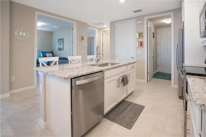 Kitchen with sink, light tile patterned floors, a kitchen island with sink, and stainless steel appliances