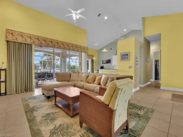 Living room featuring high vaulted ceiling, light tile patterned flooring, and ceiling fan