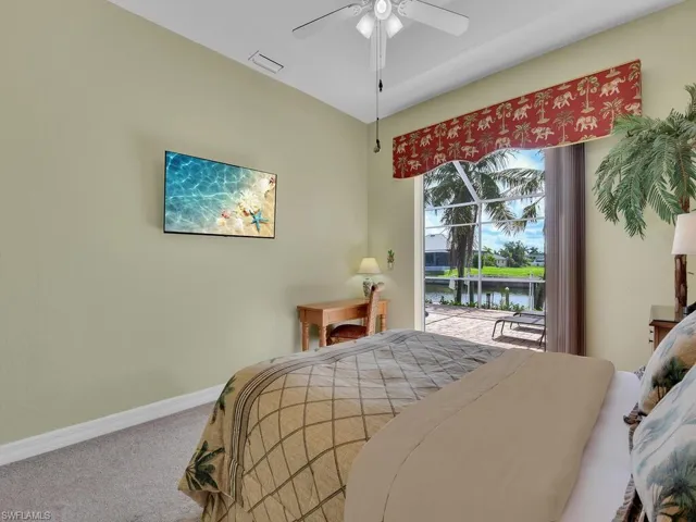 Carpeted bedroom featuring access to exterior, a water view, and ceiling fan
