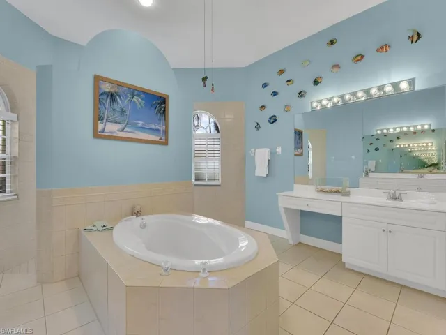 Bathroom with lofted ceiling, vanity, tile patterned floors, and tiled tub