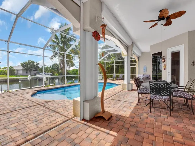 View of swimming pool featuring glass enclosure, a water view, ceiling fan, and a patio