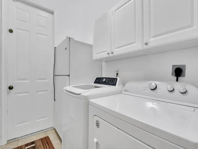 Laundry room featuring washing machine and dryer, cabinets, and light tile patterned flooring