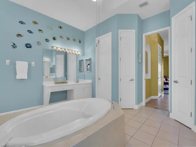 Bathroom featuring tile patterned flooring, vanity, and tiled tub
