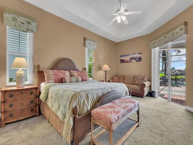 Carpeted bedroom featuring multiple windows, access to outside, ceiling fan, and a raised ceiling