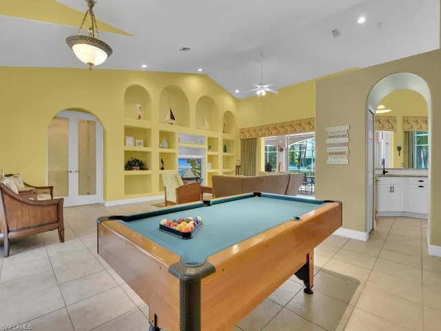 Game room featuring built in shelves, lofted ceiling, light tile patterned floors, and ceiling fan