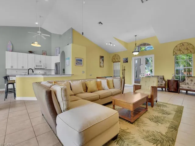 Living room with high vaulted ceiling, light tile patterned floors, and ceiling fan