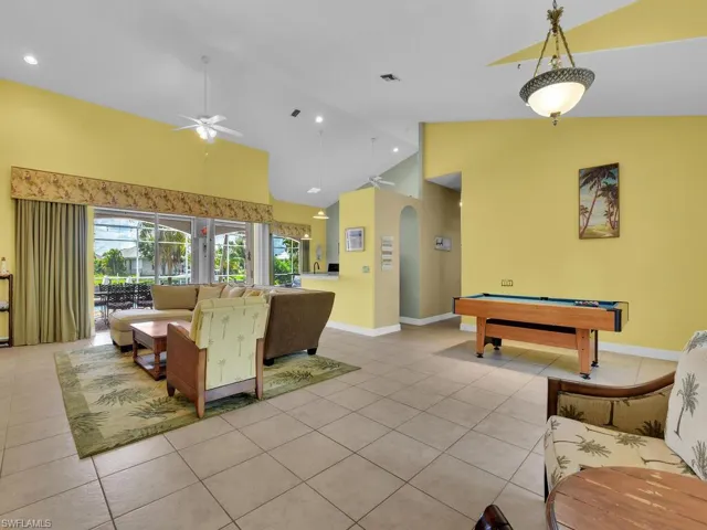 Living room with light tile patterned flooring, ceiling fan, billiards, and high vaulted ceiling
