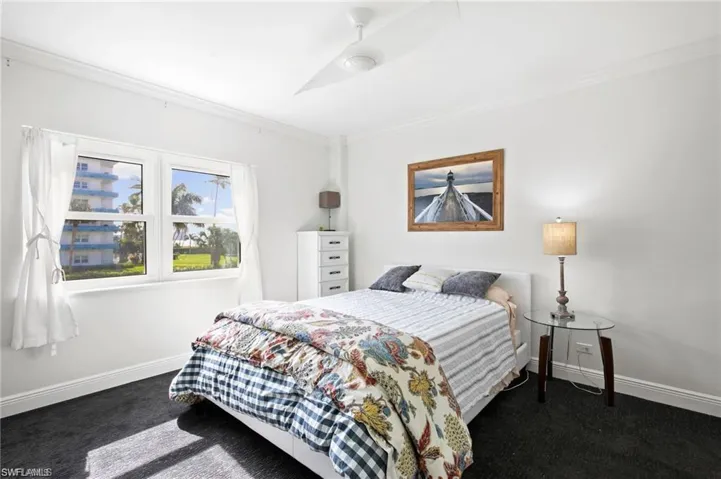 Bedroom featuring ornamental molding, dark colored carpet, and ceiling fan