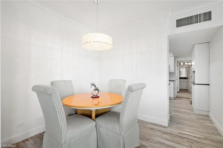 Dining space with ornamental molding and light hardwood / wood-style flooring
