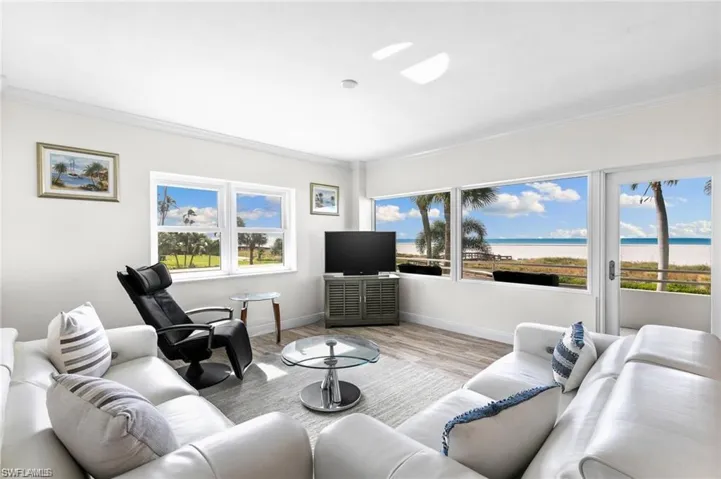 Living room featuring a healthy amount of sunlight, wood-type flooring, a water view, and crown molding